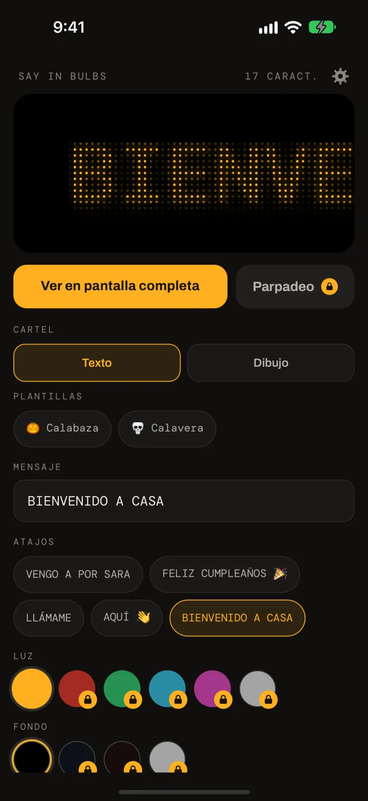 El editor de Say In Bulbs: una vista previa en matriz de puntos ámbar de BIENVENIDO A CASA, el botón Ver en pantalla completa, los dibujos listos Calabaza y Calavera, el campo del mensaje, los atajos y las muestras de color de luz y de fondo.