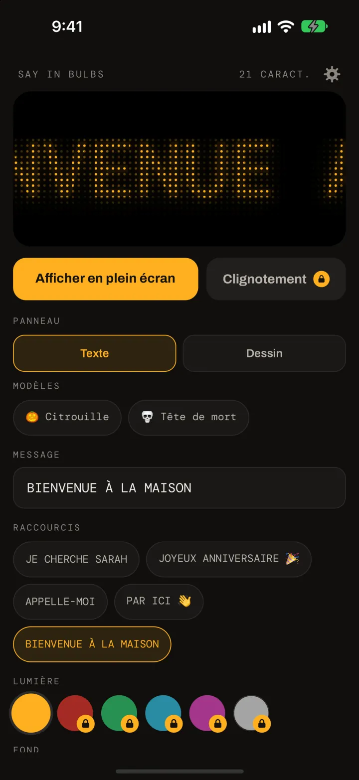 L’éditeur de Say In Bulbs : un aperçu à matrice de points ambre affichant BIENVENUE À LA MAISON, un bouton Afficher en plein écran, les modèles Citrouille et Tête de mort, le champ du message, les raccourcis et les pastilles de couleur de la lumière et du fond.
