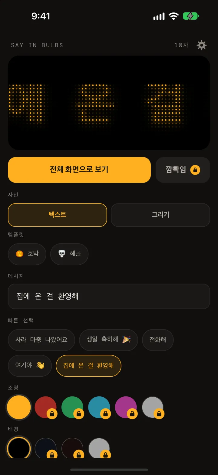Say In Bulbs 편집기: 앰버색 도트 매트릭스로 ‘집에 온 걸 환영해’를 보여 주는 미리보기, 전체 화면으로 보기 버튼, 템플릿의 호박과 해골 그림, 메시지 입력란, 빠른 선택, 조명과 배경 색상 견본.