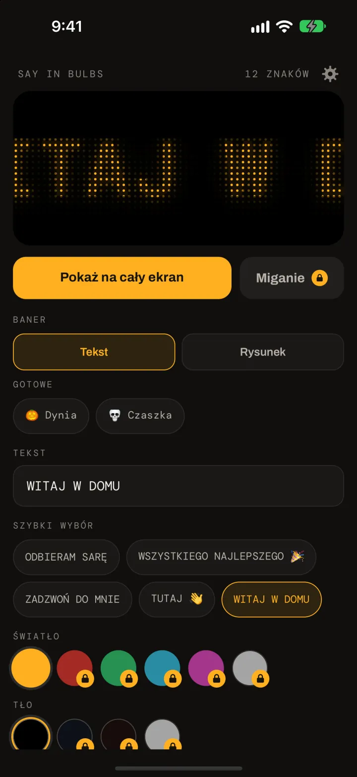 Edytor Say In Bulbs: bursztynowy podgląd z matrycy punktowej z napisem WITAJ W DOMU, przycisk Pokaż na cały ekran, gotowe rysunki Dynia i Czaszka, pole tekstowe, szybki wybór oraz próbki kolorów światła i tła.